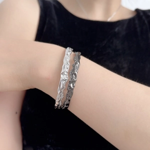 Bracciali di coppia con texture lavica irregolare indossati su sfondo di velluto nero