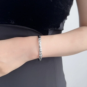 Dettaglio del bracciale rigido irregolare in argento liquido con pietre bianche