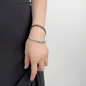 Dettaglio di bracciali argento e nero con trama lavica irregolare sul polso