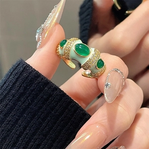 Detail view of gold ring with green enamel, emerald-cut stones and zircon inlay