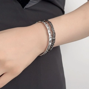Dettaglio di un paio di bracciali minimalisti con texture ondulata in argento e nero