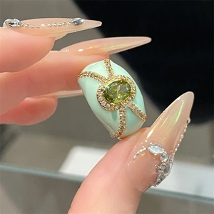 Macro detail of mint green enamel ring with oval green gem and micro-set zircon stones