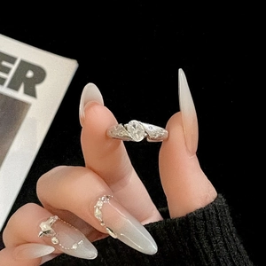 Close-up of elegant silver ring with oval clear gemstone and pavé diamonds on finger