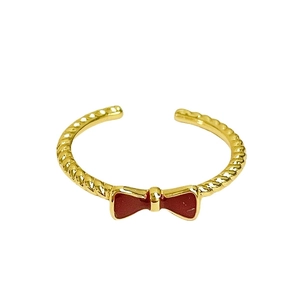 Vintage gold twist ring with red enamel bow, featuring an adjustable open band design
