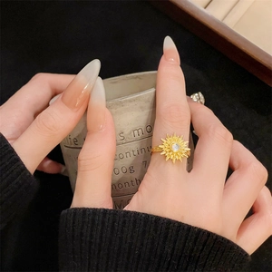 Primer plano detallado de un anillo vintage dorado en forma de sol con piedra blanca