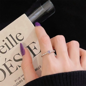 Detalle de anillo de plata con gema púrpura en la mano sobre un fondo negro elegante