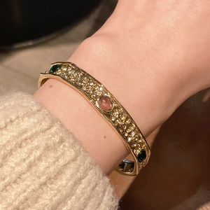 Detail of vintage gold textured bangle with three oval purple and green gemstones