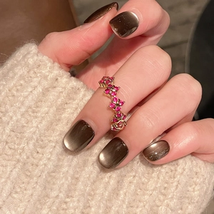 Detail of vintage gold ring featuring red floral gemstones worn by a hand with cat-eye nails