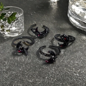 Gothic 4-piece ring set with dark red moon and snake designs on dark stone surface