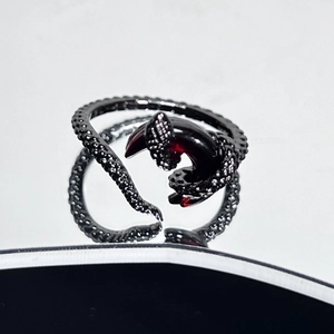 Macro shot of dark gothic snake ring with red gemstone on reflective mirror