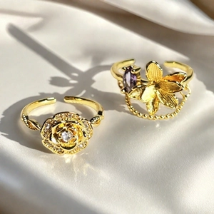 Detalle de anillos de flores doradas con gema púrpura y cadena sobre seda blanca