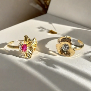 Primer plano de anillos dorados con diseño de flores y hojas de ginkgo con piedras rojas