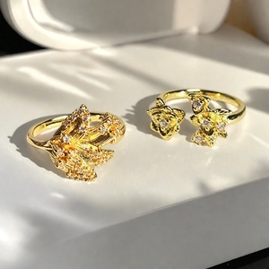 Detalle de anillos dorados vintage con flores de cristal y acentos de hojas grabadas