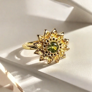 Primer plano de anillo de girasol dorado con piedra verde en fondo de bloques puros