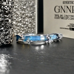Détail macro d'une bague argentée irrégulière avec incrustation bleue et accents d'étoiles
