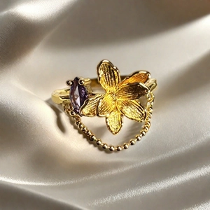 Detalle de anillo de flor vintage dorado con gema marquesa violeta y cadena colgante