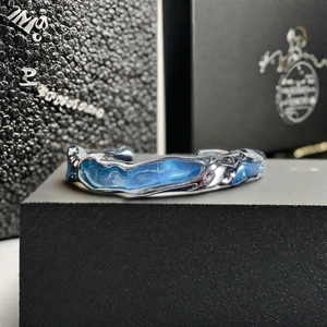 Vue macro d'une bague argentée texturée avec émail bleu et design organique fluide