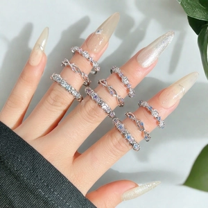 Détail de bagues élégantes avec zircons pastel et motifs floraux sur les doigts