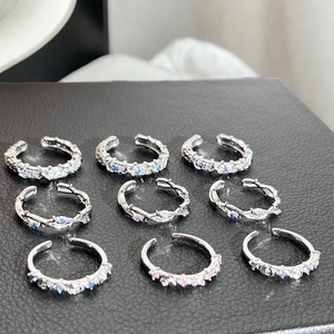 Détail de neuf bagues réglables avec zircons colorés sur présentoir en cuir noir