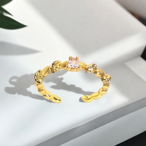 Makroaufnahme des vergoldeten Torsade-Rings mit rosa Kristall und Zirkonia-Verzierung