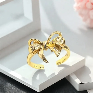 Makroaufnahme eines goldenen Schleifenrings mit feiner Textur und funkelnden Diamanten