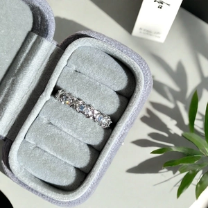 Détail d'une bague croisée en X pavée de zircons dans un écrin de luxe en velours gris