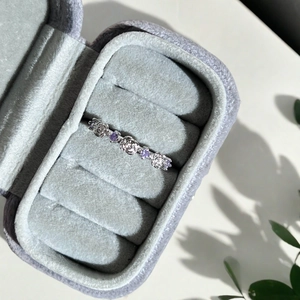 Détail d'une bague rose en argent avec zircon violet dans un écrin de velours