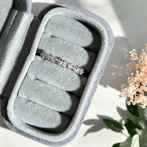 Gros plan d'une bague fleur en argent avec pierres roses dans son coffret en velours
