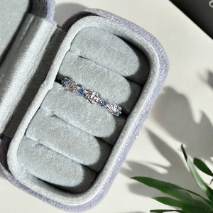 Détail d'une bague rose avec pierres bleues présentée dans un écrin à bijoux en velours