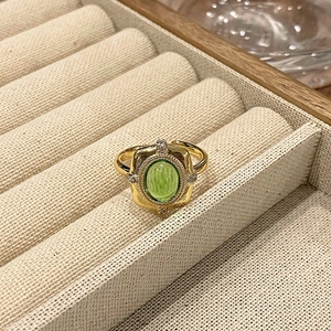 Detail van een vintage gouden ring met een groene emaille cabochon en kristalaccenten