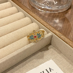 Detailopname van vintage emaille ring met rode kraal en blauwe bladmotieven