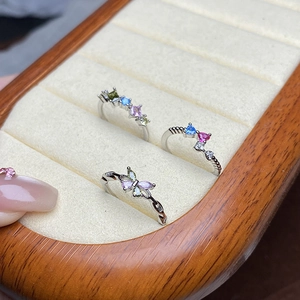 Detail von drei silbernen Zirkonia-Ringen mit bunten Schmetterlings- und Edelsteinmotiven