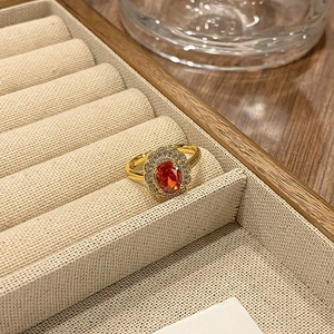 Detail van vintage emaille ring met grote oranjerode zirkoon en halo-diamantzetting