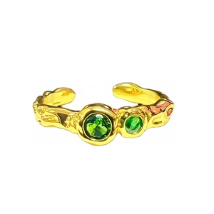 Gouden open ring met lavatectuur en twee donkergroene zirkonia op witte achtergrond