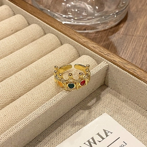 Detailopname van gouden kroonring met kleurrijke emaille hartjes in een houten doos