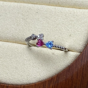 Nahaufnahme von herzförmigen rosa und blauen Steinen auf Silberring mit Mikro-Pavé