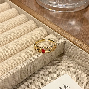 Detail van vintage gouden ring met rode ovale edelsteen en blauwe accenten in doos