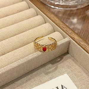 Detail van vintage gouden open ring met rode ovale steen en opengewerkte kanttextuur