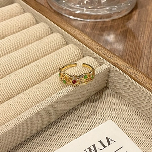 Macrodetail van een vintage gouden open ring met rode en groene edelsteen inlay