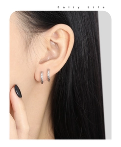 Primer plano de pendientes de aro plateados con textura martillada en una modelo