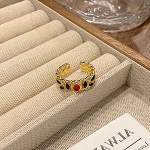 Detail van vintage emaille open ring met rode edelsteen en blauwe bladaccenten in goud