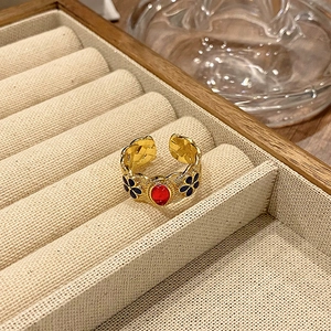 Detail van vintage verstelbare ring met rode ovale steen en bloemmotieven van emaille