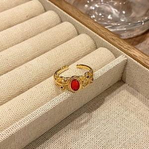 Detailopname van vintage gouden open ring met rode ovale edelsteen en bladmotief