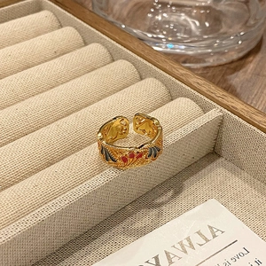 Detailopname van een vintage gouden ring met rode en zwarte emaille bloemmotieven