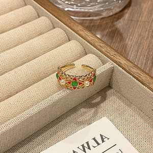 Detail van vintage opengewerkte ring met kleurrijk email en kleine witte parels