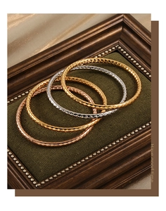 Detailansicht von vier gehämmerten Armreifen in Gold, Silber und Roségold-Finish
