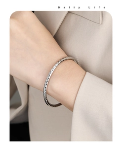 Detailaufnahme eines silbernen Armreifs mit Hammerschlag-Textur am Handgelenk einer Frau