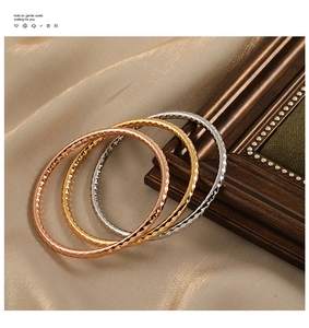 Detail von dreifarbigen strukturierten Armreifen in Roségold, Gold und Silber auf Seide