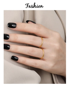 Primer plano de anillos finos dorados con circonitas sobre manos con esmalte negro de moda
