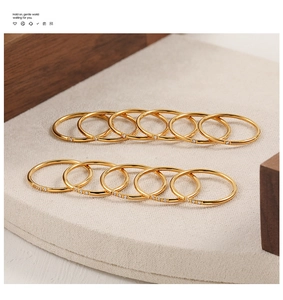 Detalle de anillos finos de titanio dorado apilados con circonitas en bandeja zen